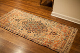 Antique ivory Senneh Baft rug with dark blue medallion and rust curvilinear motifs.