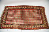 Antique Armenian rug's lower left corner with madder red harlequin diamonds and exposed foundation.
