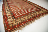Geometric beige border and worn fringe of an antique Armenian madder red harlequin rug.