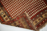 Corner detail of antique Armenian rug with madder red harlequin and geometric border motifs.