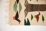 Cream fringe on a pictorial Romanian kilim, showing a brown duckling and green trees.