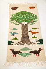 Romanian pictorial kilim detail of a dark brown duckling, green foliage, and fringe.