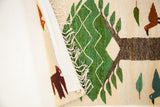 Folded Romanian Pictorial Kilim showing a green tree, brown bird, and cream mounting sleeve with fringe.