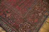 Detailed corner of antique Kurdish runner, rich red field, geometric motifs, and expert historic repair.