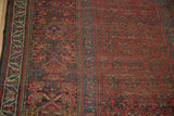 Hand-knotted antique Kurdish rug's intricate border and red field with repeating boteh.