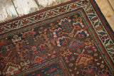 Antique Kurdish rug corner detail, revealing hand-knotted red and blue boteh pattern and fringe.