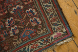 Kurdish rug corner detail, showing geometric border, worn fringe, and a rewoven pink area.