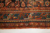 Vintage Hamadan rug detail: ornate teal, rust, and dark blue border patterns with tattered edge.