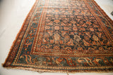 Worn fringe, dark blue field, and teal border detail on vintage Hamadan rug.