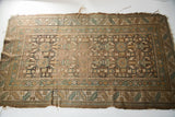 Frayed edges and muted geometric patterns of a tattered circa 1915 Caucasian rug.
