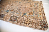 Antique rug corner, geometric tribal patterns in ivory, chocolate brown, medium blue, with wear.