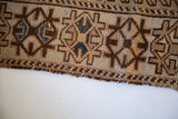 Antique Caucasian rug edge, showing tribal geometric pattern in ivory, chocolate, and blue.