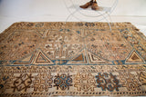 Antique Caucasian rug's geometric border and field detail in ivory, chocolate, and blue tribal motifs.