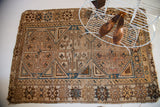 Antique Caucasian tribal rug corner showing geometric ivory, chocolate, and blue patterns.