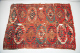 Bottom right of vintage tribal rug, highlighting red, teal pomegranate patterns, wear, and holes.