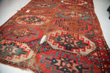 Bohemian tribal rug displaying significant wear, holes, and tattered edge.