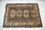 Upper corner of an antique Caucasian rug, featuring dark indigo and beige geometric patterns.