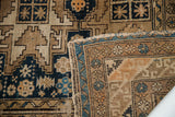 Close-up of folded antique Caucasian rug, revealing fine weave, geometric patterns, and indigo.