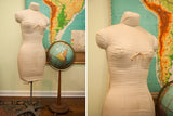 Mid century dress form with light beige cotton canvas cover and metal stand.