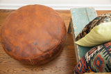 Antique leather pouf ottoman with rich orangey-brown patina and embossed fan motif details.