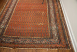 Antique Persian Serbend rug corner displaying madder rust field, geometric borders, and aged fringe.