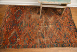 Lower corner of an Antique Beshir rug with deep brick red field, unique blue guls, and visible aged texture.