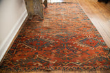 Close-up of antique Beshir rug, displaying worn pile, deep brick red hooked guls, blue border.