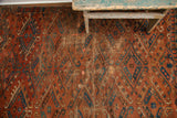 Worn antique Turkmen rug detail: deep brick red field, unique blue guls with oversize hooks.