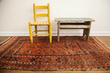 Antique Belouch rug runner displays repeating geometric motifs in burnt orange and indigo.