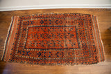 Upper corner of antique Belouch runner with geometric motifs, worn fringe, and time-softened tones.