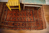 Antique Belouch rug side border and central geometric pattern in time-softened tones.