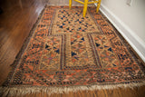 Antique Belouch rug corner, natural fringe, peachy brick red border, and walnut brown field.