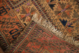 Antique Belouch rug corner with fringe, showing walnut brown pile and peachy brick red reverse.