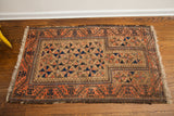 Lower corner of antique Belouch rug, showing peachy brick red border and geometric field.
