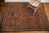 Antique Tribal Shiraz rug corner, deep red field, mallard green serrated leaf motifs.