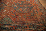 Antique Tribal Persian Shiraz rug with deep red field and blue-green serrated leaf motifs.