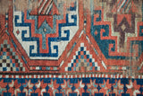 Textured geometric motifs with vibrant red, blue, and ivory from the antique Kazak rug.