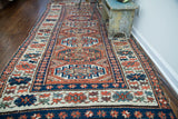 Intricate geometric motifs and alternating colors on the antique Kazak runner's border.