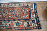 Antique Kazak runner end showcasing deep blue and terracotta geometric borders with authentic patina.