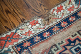 Worn edge of an antique Kazak rug, showing coral, blue patterns and natural wefting.