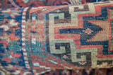 Hand-knotted antique Kazak rug detail with geometric patterns in blue, red, and beige.