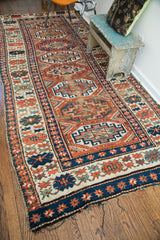 Kazak rug's worn corner, rich blue border, and colorful geometric motifs.