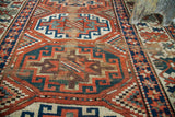 Antique Kazak runner detail: geometric patterns in deep red, blue, ivory, showing historic wear.