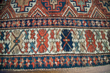 Intricate geometric border detail of antique Kazak runner with terracotta, navy, and cream tones.