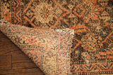 Antique tribal rug's corner with worn walnut pile and visible woven foundation.