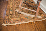 Antique tribal rug detail: Herati pattern, walnut chocolate field, rusty grapefruit red, and worn fringe.