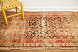 Detail of antique Samarkand runner: faded black, orange, beige geometric patterns, authentic wear.