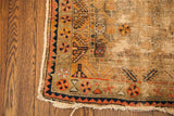 Worn antique Samarkand rug corner with exposed foundation, geometric patterns, and tattered fringe.