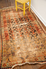 Visible wear, holes, and tatter on black and orange geometric patterns of an antique Samarkand runner.