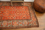 Vintage Malayer rug's corner shows red field, jewel-toned border, and fringed edge.